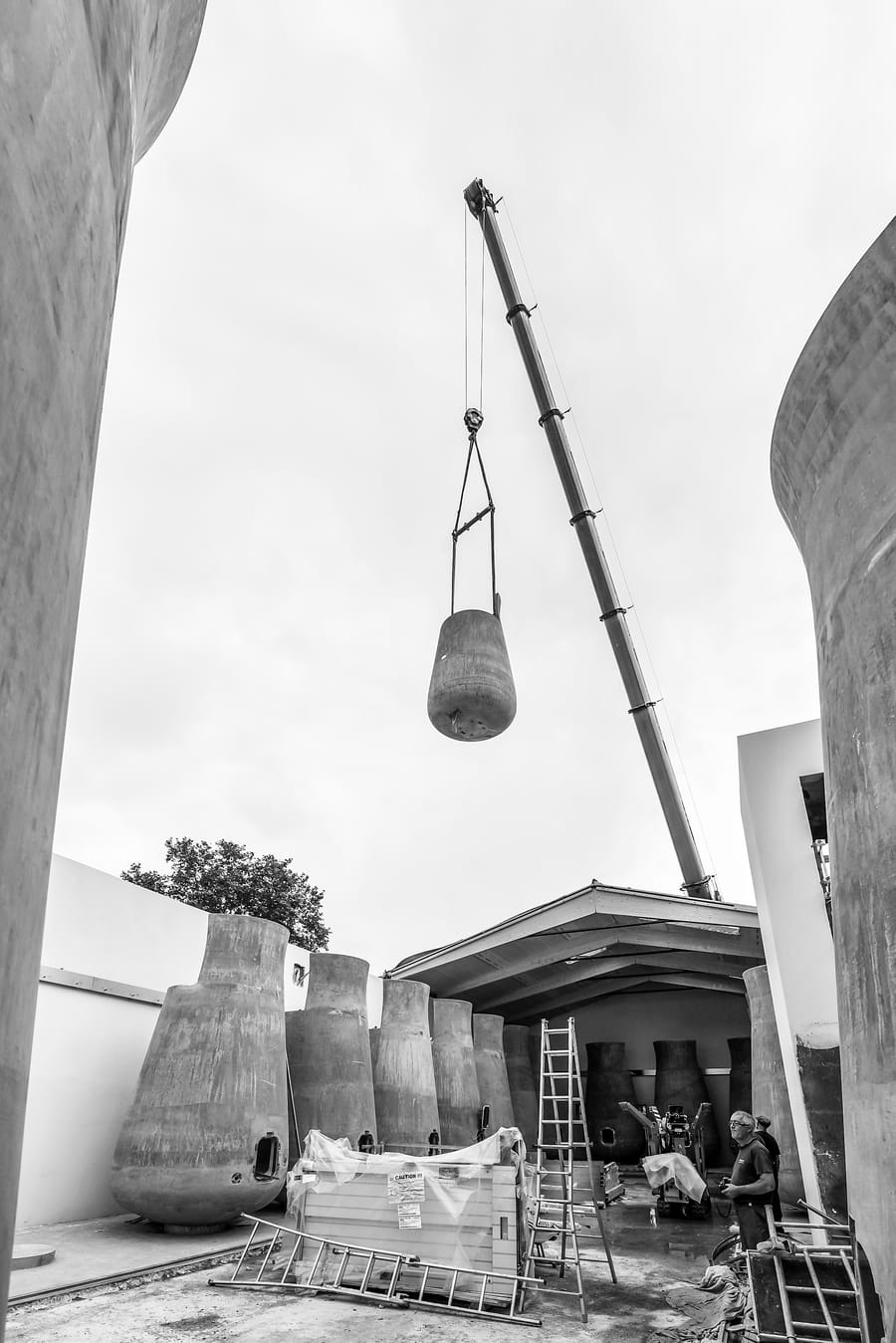 Grue mobile soulevant une cuve tronconique en béton sur le chantier de construction d'un chai, Château Beauregard à Pomerol