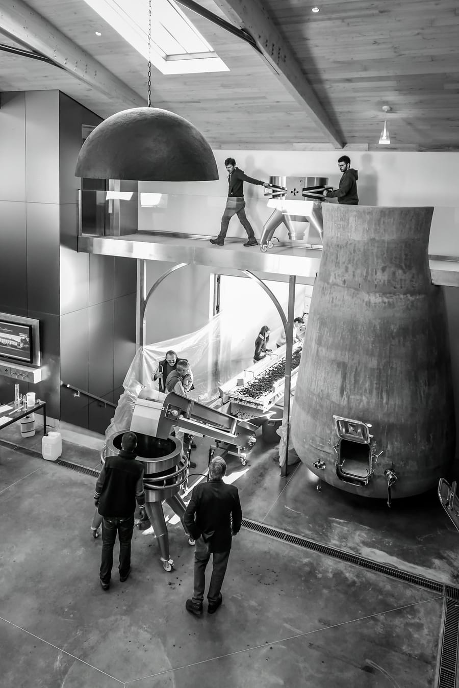 Vignerons travaillant autour des cuves et de la table de tri dans un chai moderne, Château Beauregard à Pomerol