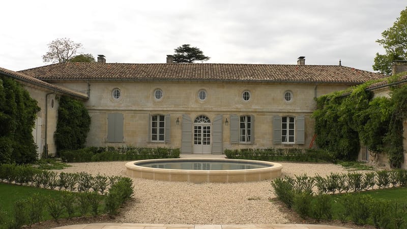 Cour intérieure en pierre d'un domaine avec un bassin circulaire et des haies taillées, au Château Beauregard