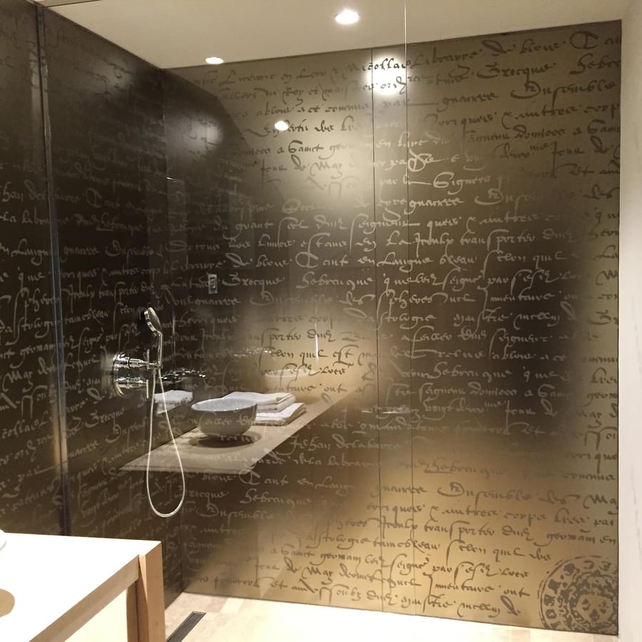 Douche et vasque dans une salle de bains au mur sombre décoré de calligraphie au Château Beauregard