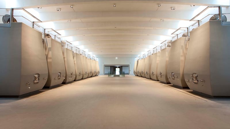 Alignement symétrique de cuves en béton incurvées dans un chai moderne et lumineux, Château Cheval Blanc à Saint-Émilion