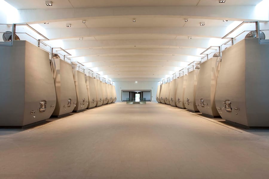Alignement symétrique de grandes cuves à vin en béton au sein d'un chai de vinification contemporain, Château Cheval Blanc à Saint-Émilion