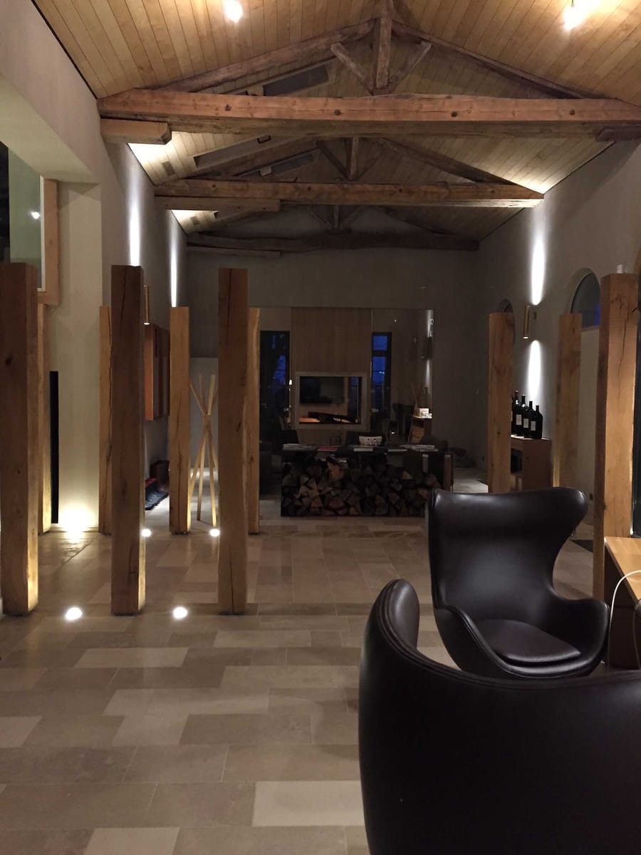 Aménagement intérieur d'un espace avec charpente en bois apparente, poteaux en bois et fauteuils en cuir, Château Cheval Blanc à Saint-Émilion