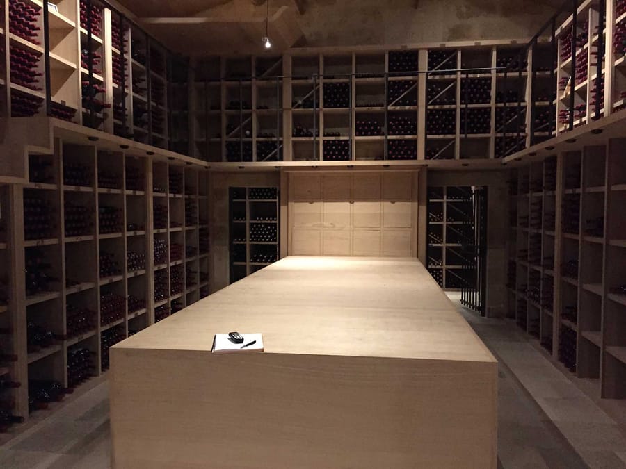 Cave à vin contemporaine en bois équipée de casiers remplis de bouteilles autour d'une grande table centrale, Château Cheval Blanc à Saint-Émilion