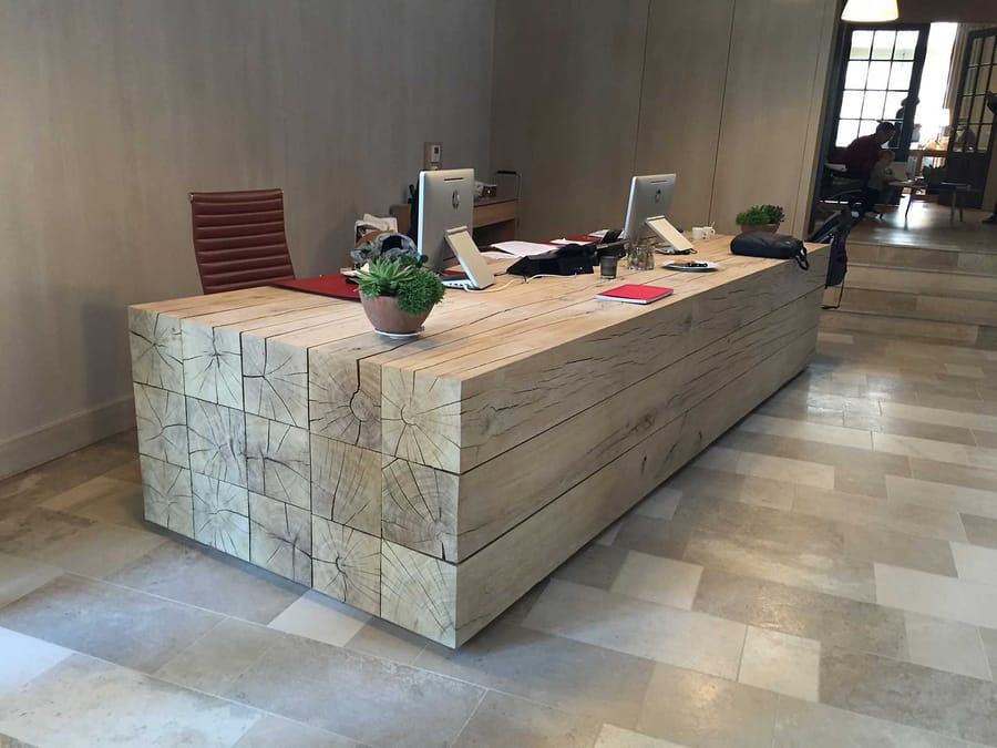 Grand bureau d'accueil en poutres de bois massif avec écrans d'ordinateur, dans un intérieur conçu par un cabinet d'architecture, Château Cheval Blanc à Saint-Émilion