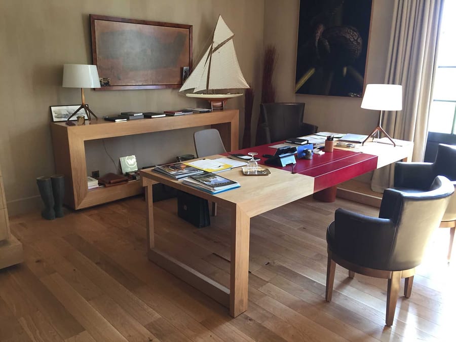 Grand bureau en bois clair et cuir rouge entouré de fauteuils, dans un espace aménagé par un architecte, Château Cheval Blanc à Saint-Émilion