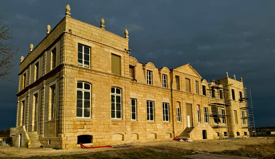 La façade en pierre blonde sous un ciel d'orage