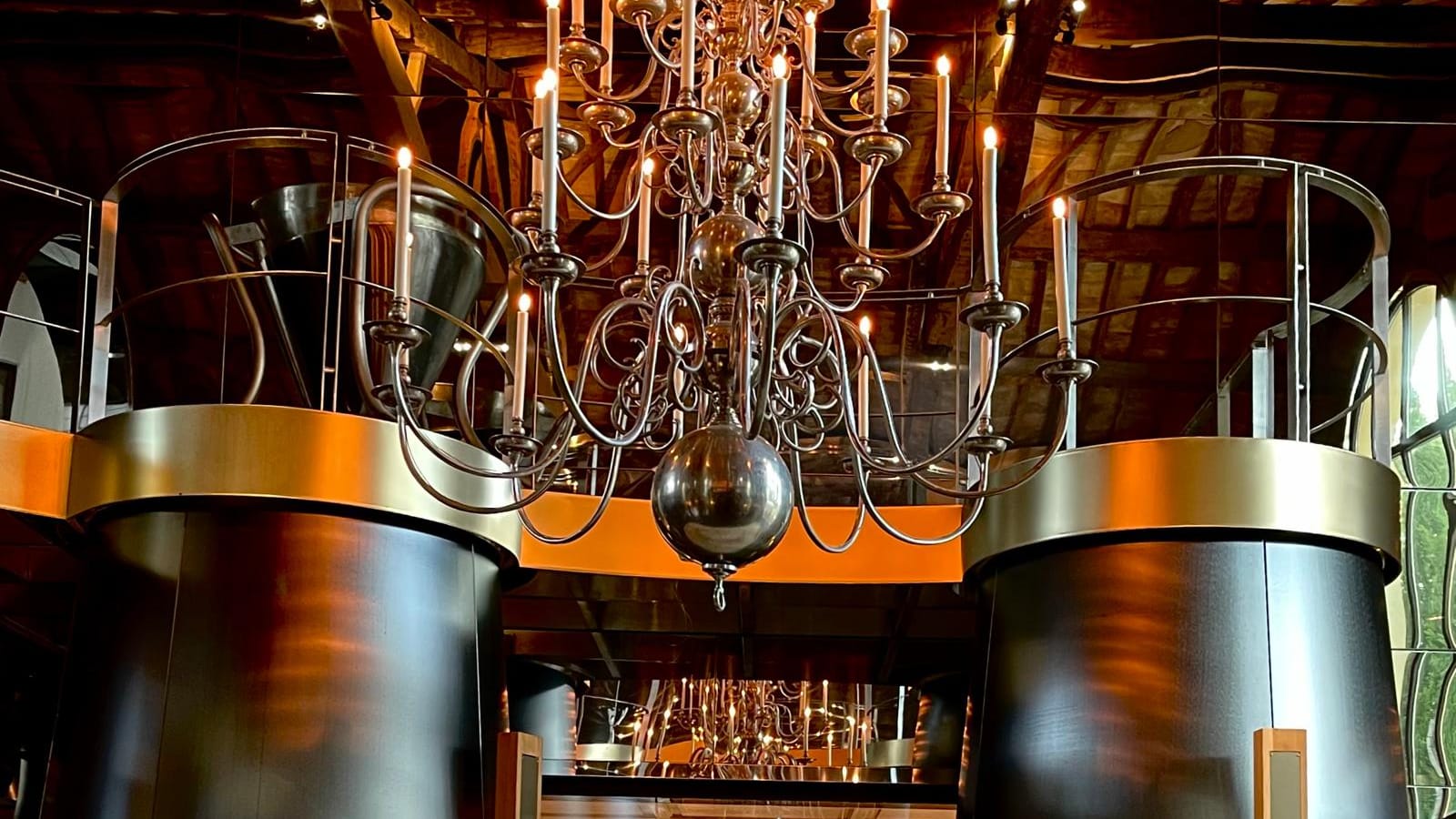 Large metal tanks and wooden barrels lined up in the center of a vat room at a winery in La Gaude