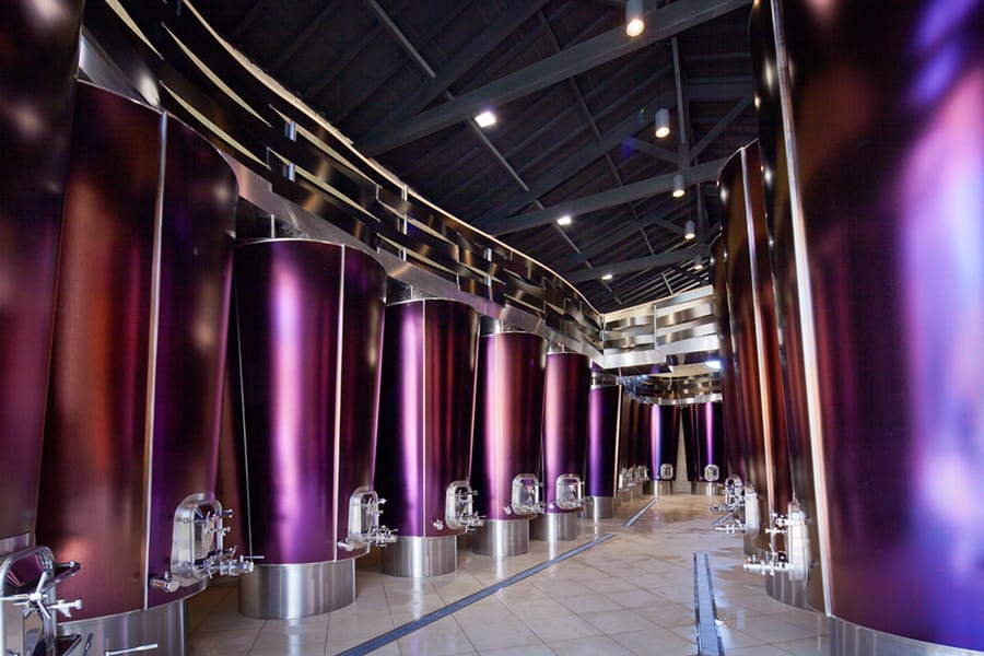 Alignement de cuves vinicoles violettes en acier inoxydable dans un cuvier au design moderne, Château La Gaffelière à Saint-Émilion