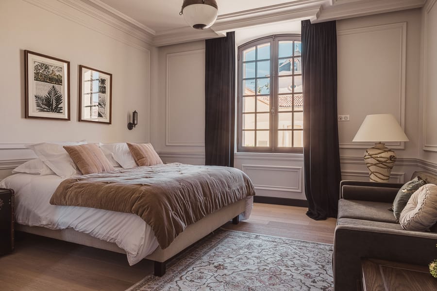 Chambre élégante dotée d'un lit double, d'un canapé et d'une grande fenêtre voûtée, Château Laffitte Carcasset à Saint-Estèphe