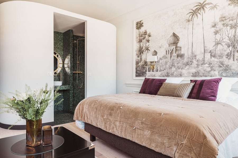 Chambre spacieuse avec un grand lit beige, du papier peint exotique et une salle de bains attenante en mosaïque verte, Château Laffitte Carcasset à Saint-Estèphe