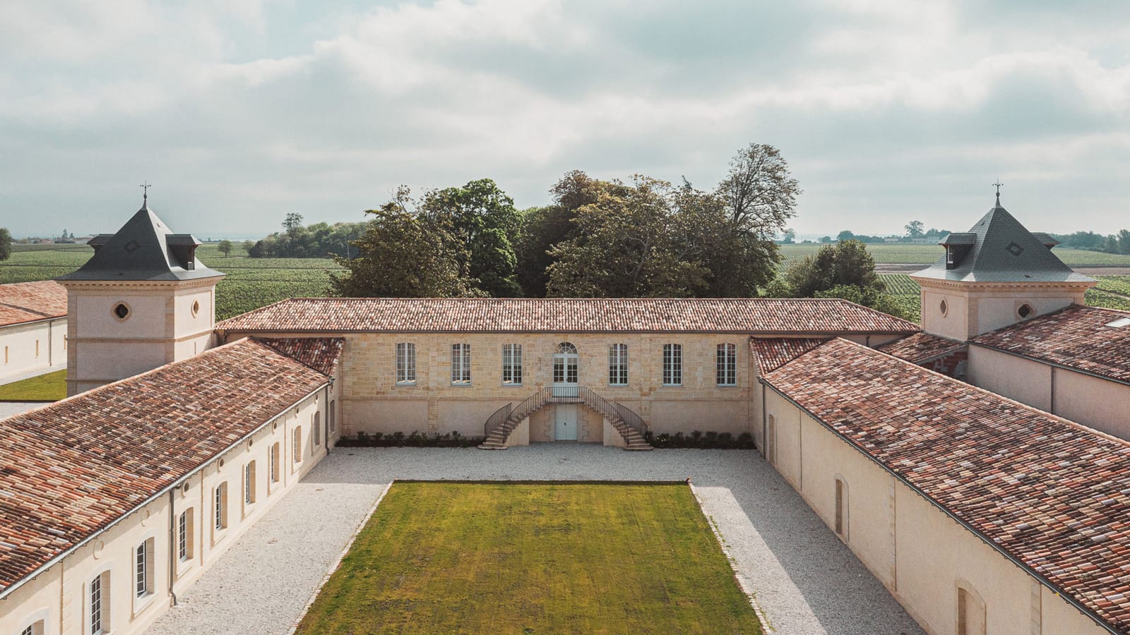 Vue en hauteur de la cour intérieure d'un domaine viticole aux bâtiments en pierre entouré de vignes, Château Laffitte Carcasset à Saint-Estèphe
