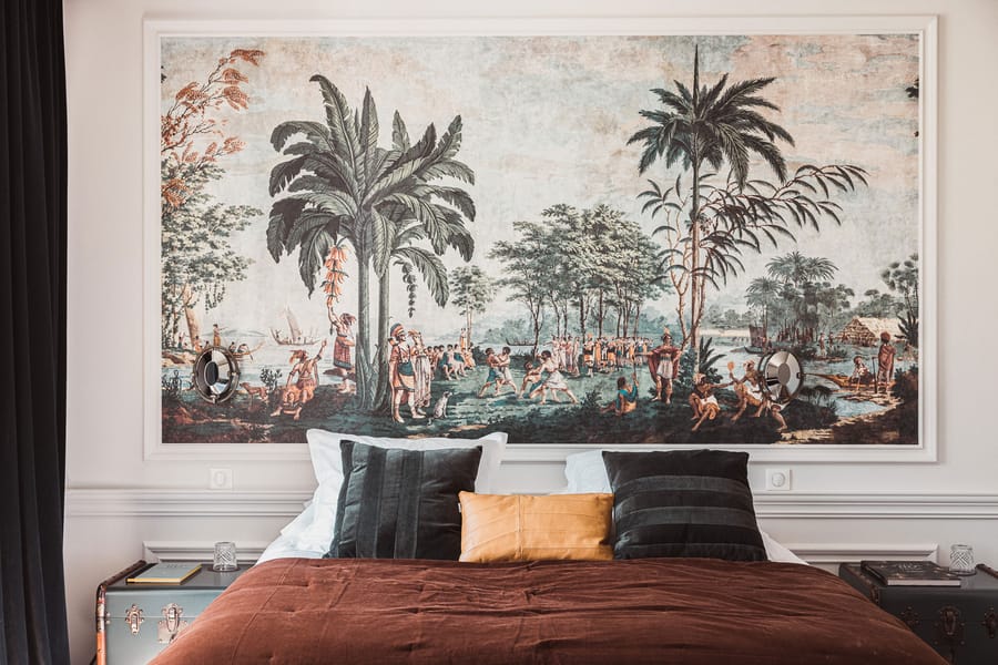Lit garni de coussins devant un papier peint panoramique tropical encadré dans une chambre élégante, Château Laffitte Carcasset à Saint-Estèphe