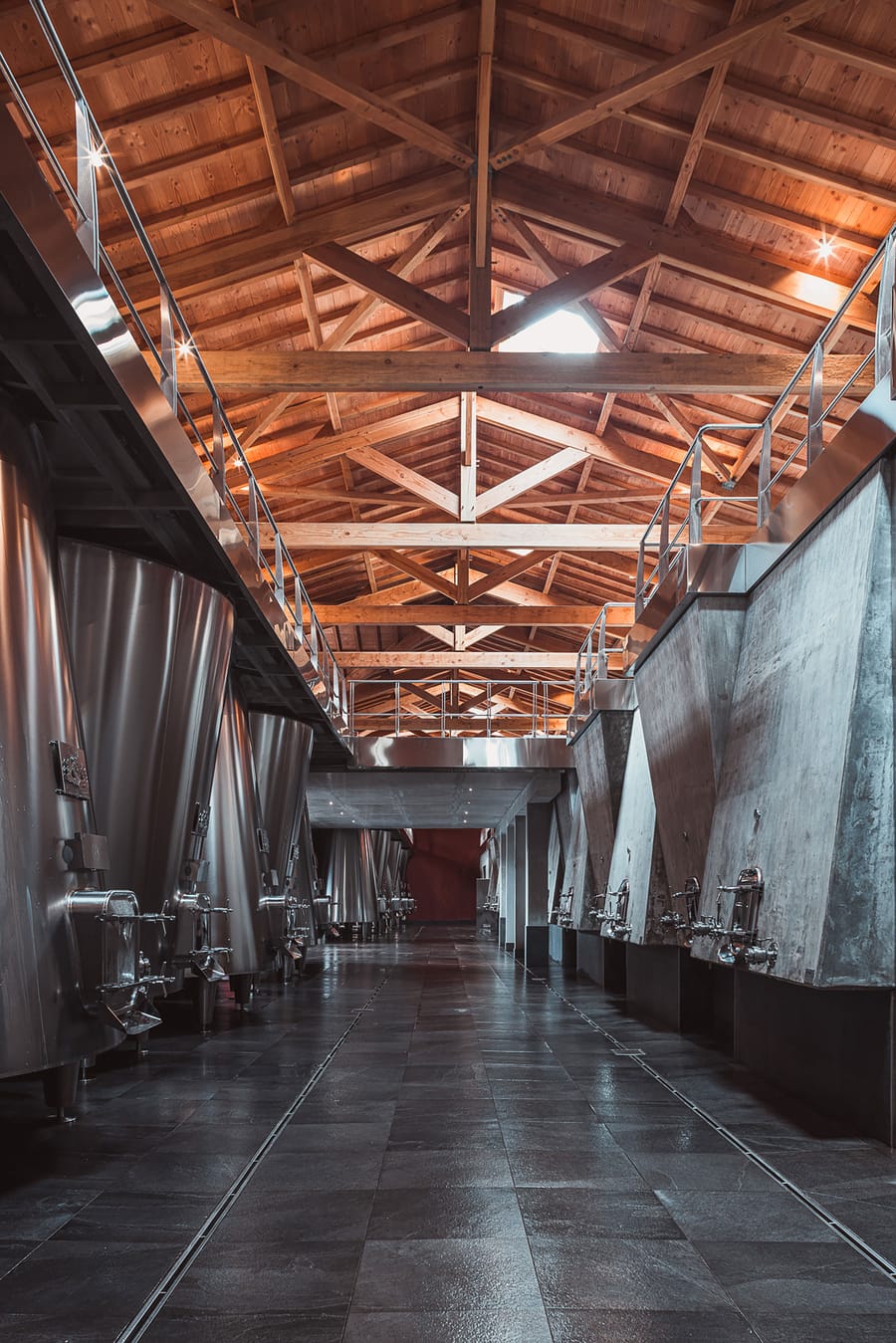 Cuvier moderne alignant des cuves en inox et en béton sous une charpente en bois dans un domaine viticole, Château Laffitte Carcasset à Saint-Estèphe
