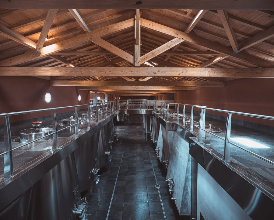 Cuvier de vinification aux cuves en inox sous une charpente en bois apparent, Château Laffitte Carcasset à Saint-Estèphe