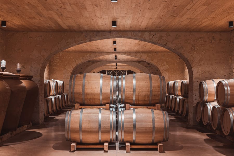Fûts de chêne alignés sous des voûtes en pierre dans un chai à vin, Château Laffitte Carcasset à Saint-Estèphe