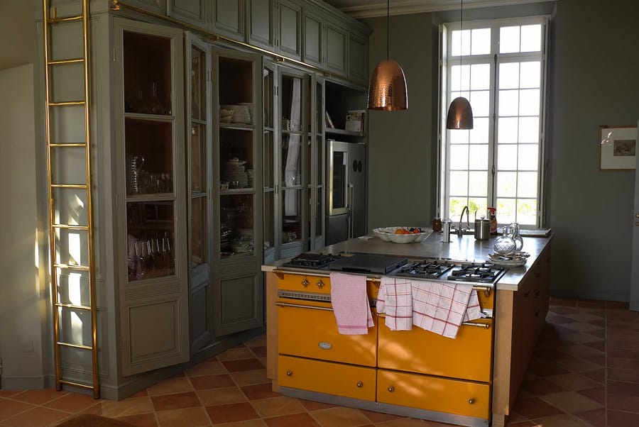 Grande cuisine aménagée avec un piano de cuisson jaune, un îlot central et des placards intégrés, Château Lafon-Rochet à Saint-Estèphe