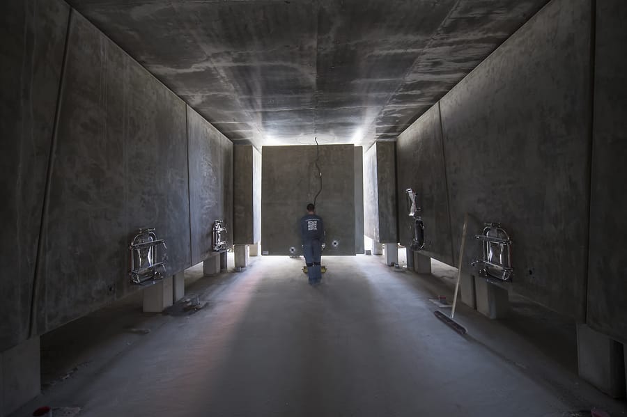 Un homme de dos au centre d'un cuvier contemporain alignant des cuves en béton, dans un chai, Château Lafon-Rochet à Saint-Estèphe