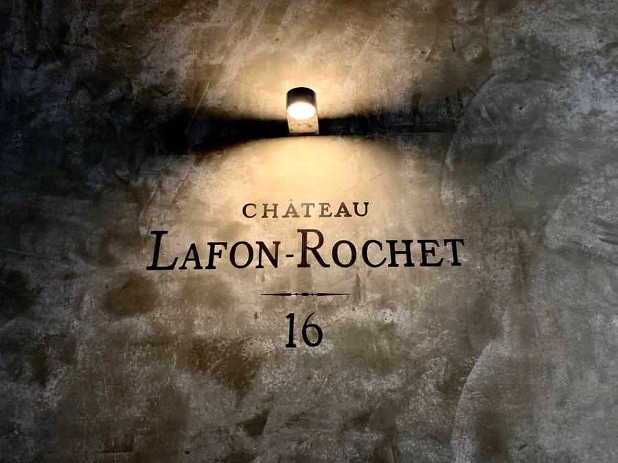 Inscription du Château Lafon-Rochet éclairée par un spot lumineux sur un mur en béton brut, à Saint-Estèphe