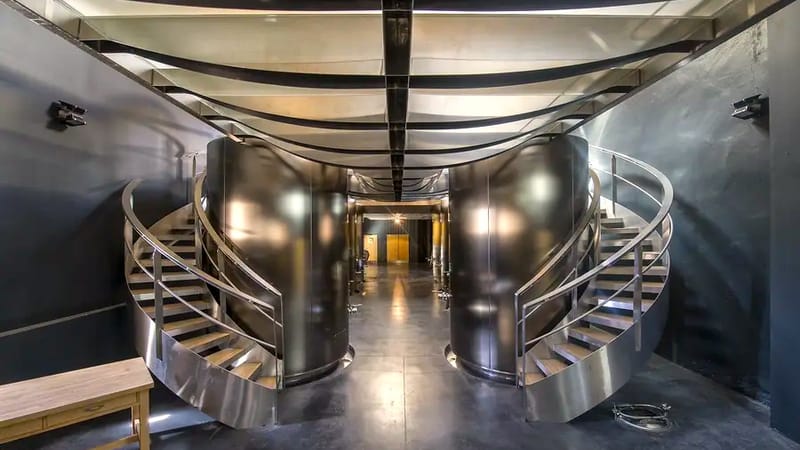 A worker standing in the central aisle of a modern vat room surrounded by concrete vats at the winery, Château Lafon-Rochet in Saint-Estèphe
