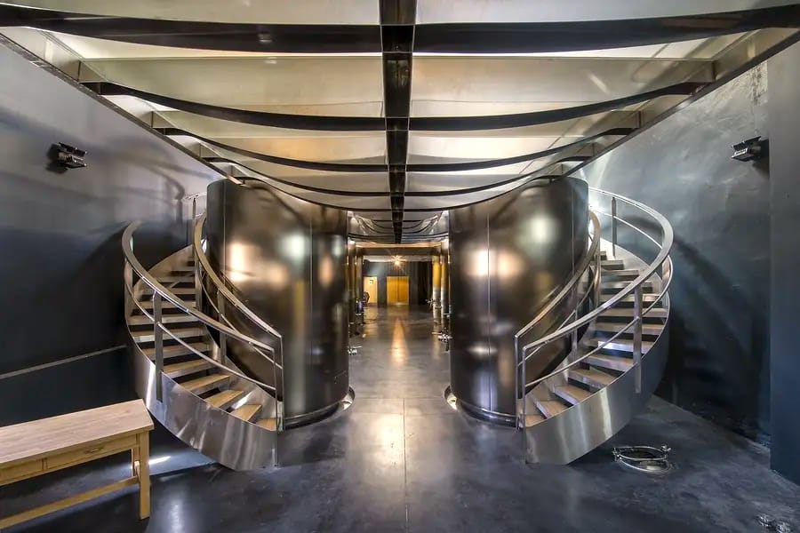 A worker standing in the central aisle of a modern vat room surrounded by concrete vats at the winery, Château Lafon-Rochet in Saint-Estèphe