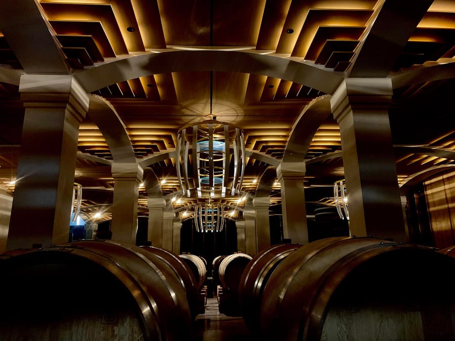 Alignement de foudres en bois dans un chai à vin moderne au plafond éclairé, dans un domaine viticole, Château Montlabert à Saint-Émilion