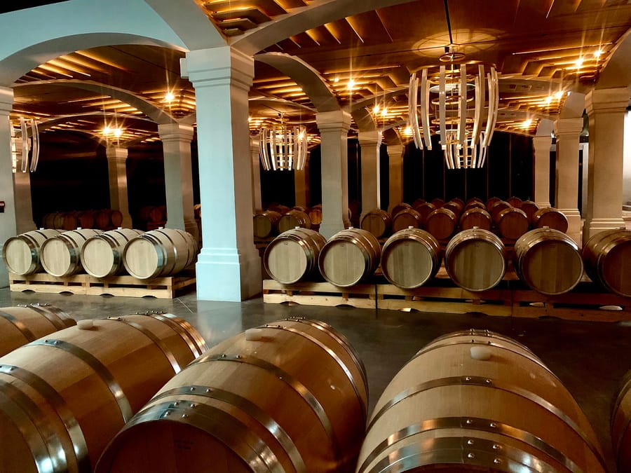 Barriques de vin en bois alignées sous des voûtes éclairées dans un chai moderne, Château Montlabert à Saint-Émilion