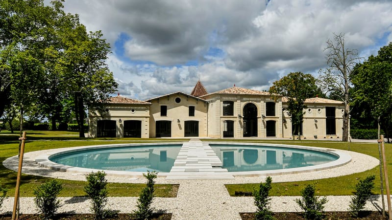 Bâtisse en pierre et son grand bassin circulaire disposé dans un parc paysager arboré, Château Montlabert à Saint-Émilion