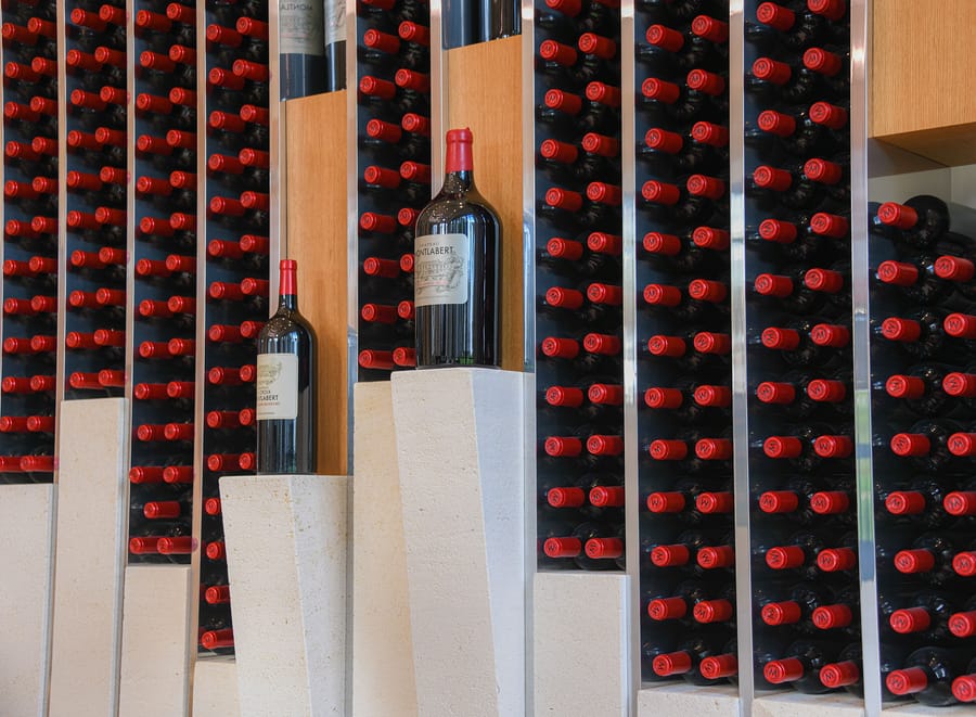 Bouteilles de Château Montlabert présentées sur des socles en pierre au cœur d'un casier à vin contemporain, à Saint-Émilion