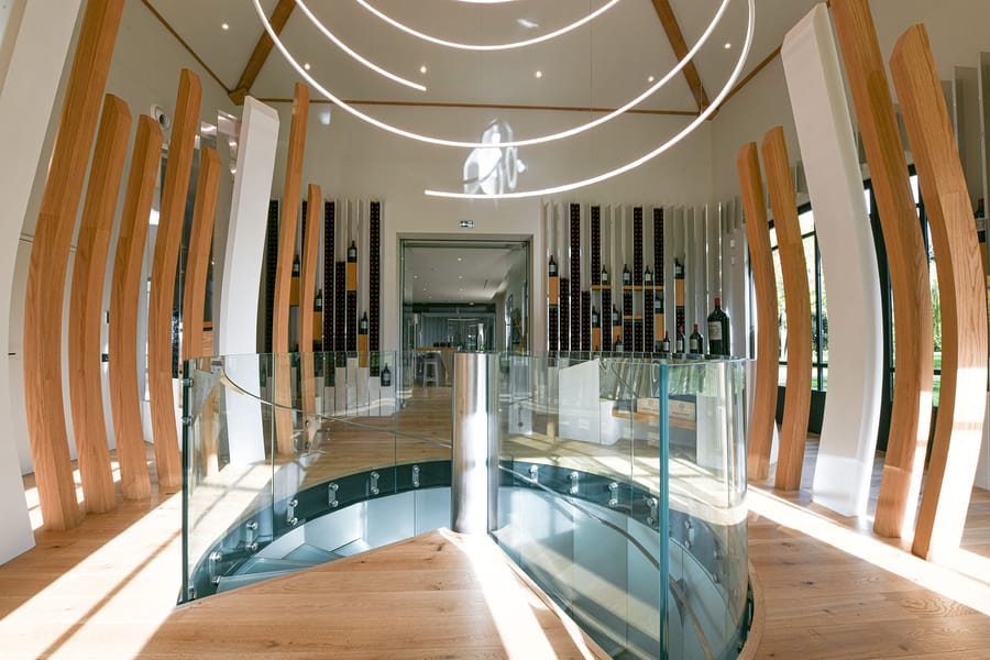 Intérieur contemporain d'une salle de dégustation habillée de lattes de bois et surplombant un escalier vitré, Château Montlabert à Saint-Émilion