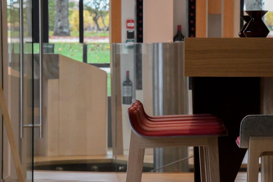 Tabourets de bar modernes en bois et assise rouge devant un comptoir de dégustation, Château Montlabert à Saint-Émilion