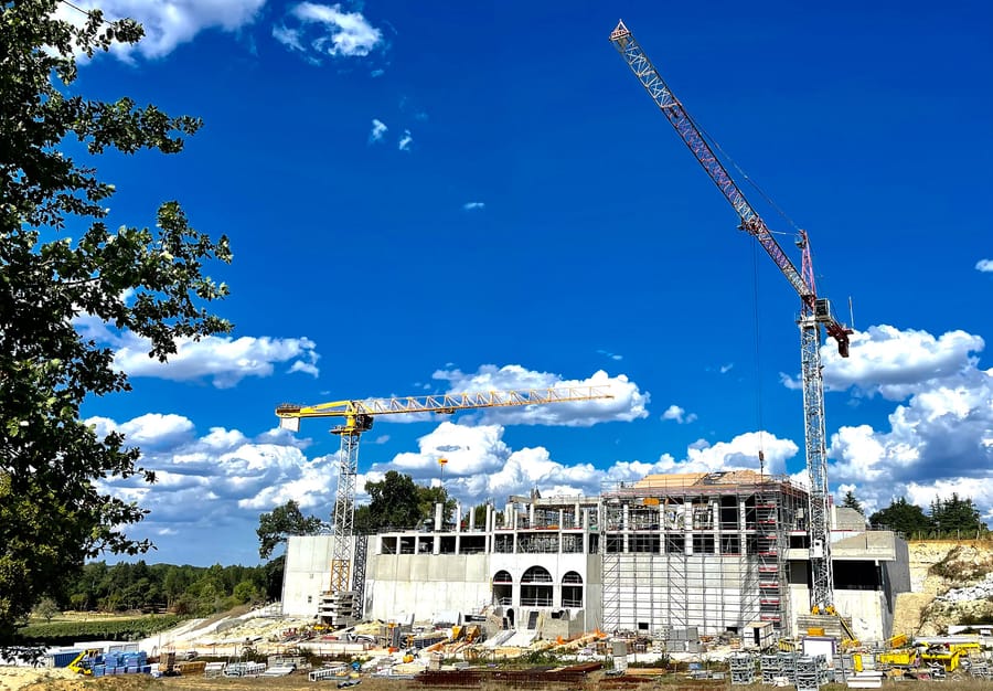 Chantier de construction d'un bâtiment avec deux grues de chantier sous un ciel nuageux, Château Plain Point à Fronsac