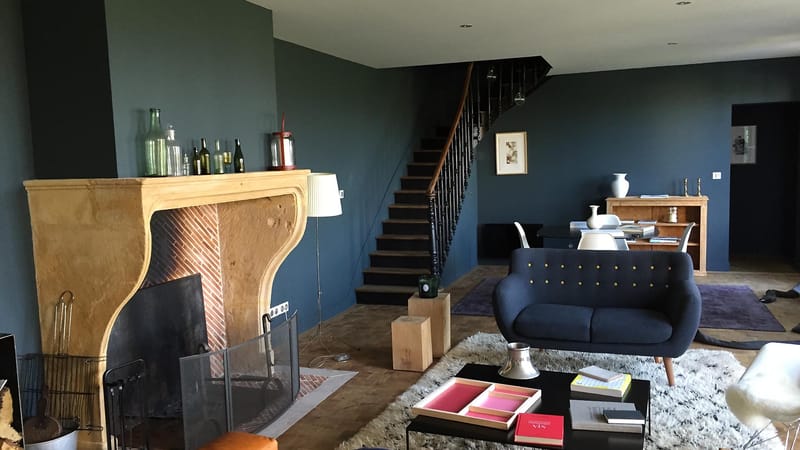 Salon au style contemporain aux murs bleu foncé, doté d'une grande cheminée en pierre et d'un escalier en bois