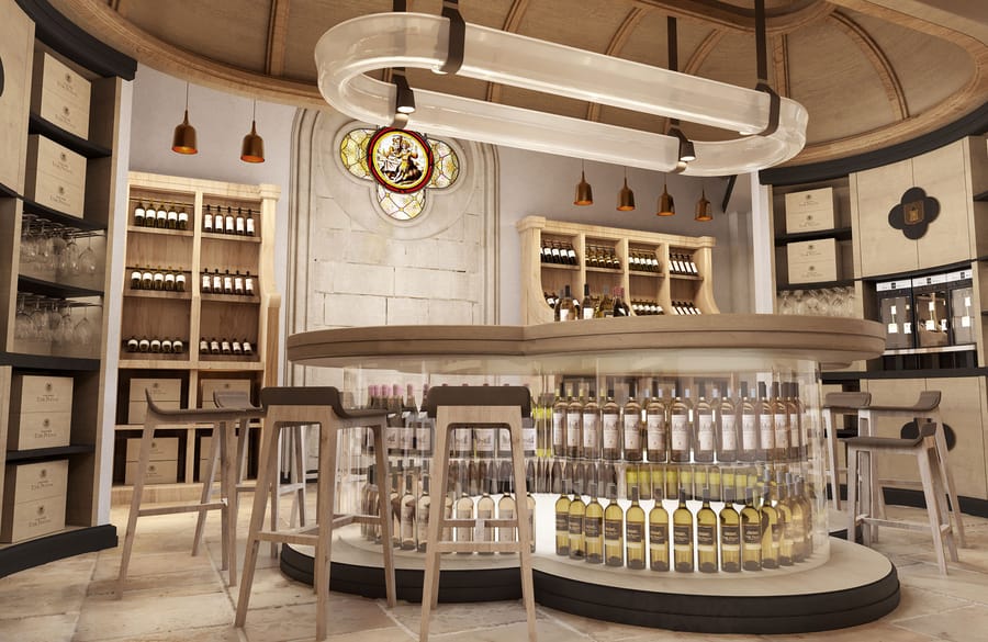 Espace de dégustation moderne dans un cadre ancien avec comptoir rond vitré, bouteilles de vin et tabourets en bois, au Château Tour Prignac