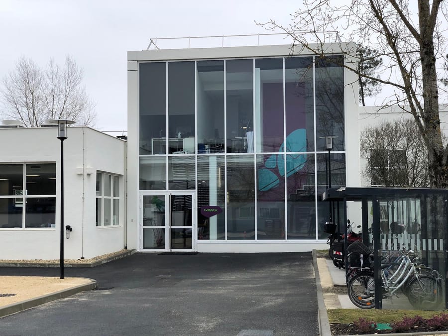 Façade moderne en verre du bâtiment Merck et son abri à vélos, conçue par un cabinet d'architecture, Merck Biodevelopment à Martillac