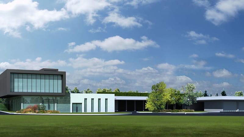 Bâtiment professionnel moderne aux baies vitrées et structure contemporaine entouré d'espaces verts sous un ciel nuageux, à Mailly-le-Camp