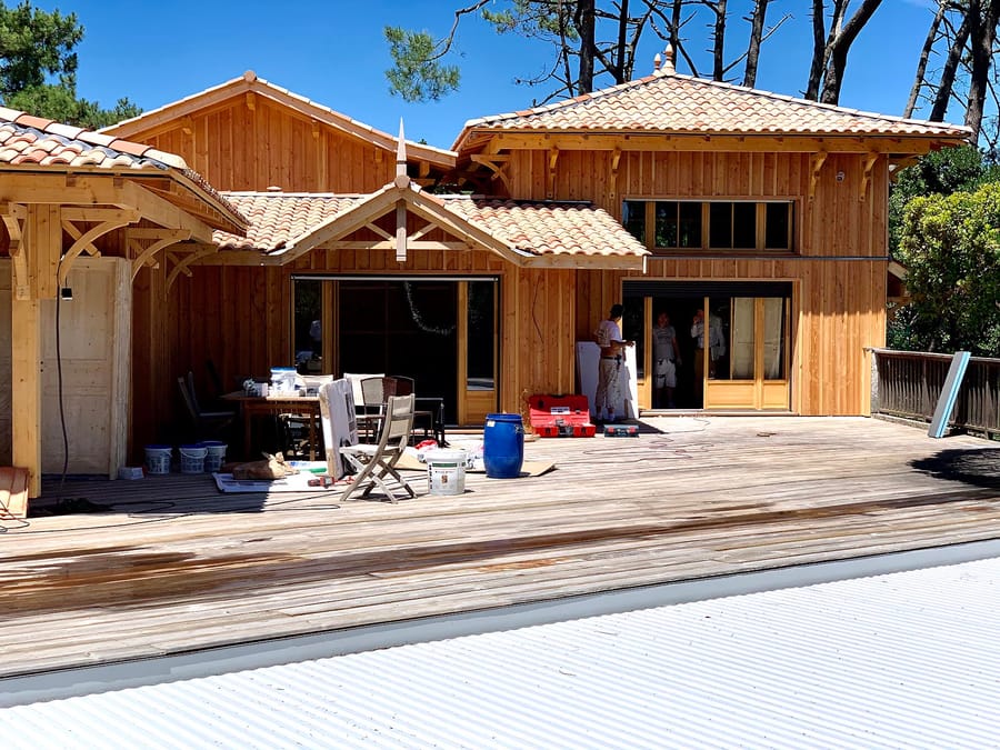 Artisans au travail sur la grande terrasse d'une villa en bois couverte de tuiles, au Cap Ferret
