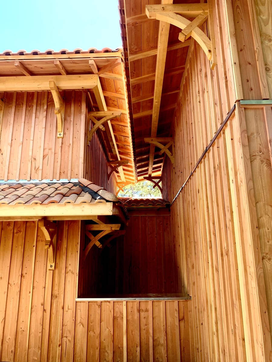 Bardage vertical en bois et détails de charpente sous un toit de tuiles en terre cuite d'une villa, au Cap Ferret
