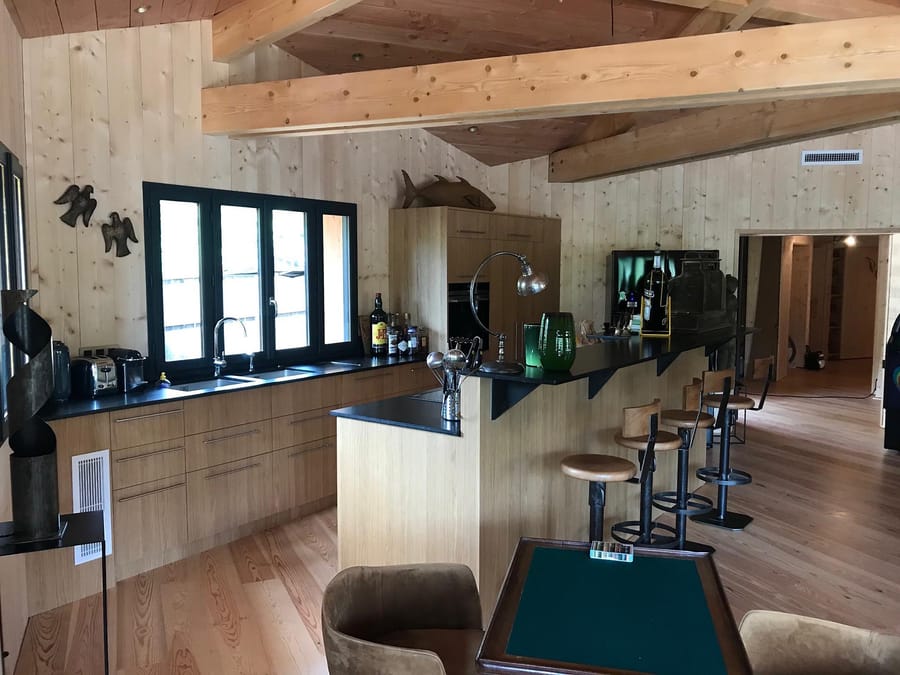 Cuisine ouverte en bois avec comptoir bar, tabourets et poutres apparentes au plafond dans une villa, au Cap Ferret