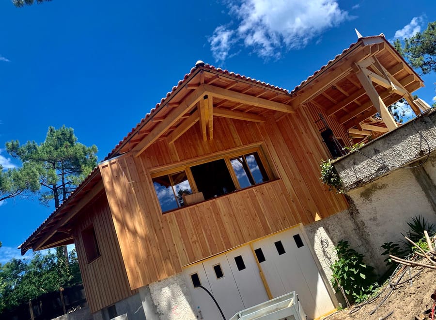 Extension en bardage bois d'une maison individuelle avec garage sous un ciel bleu, au Cap Ferret