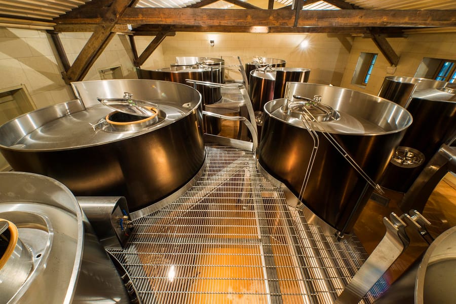 Cuves en inox installées sous une charpente en bois dans un cuvier viticole, Château d'Yquem à Sauternes