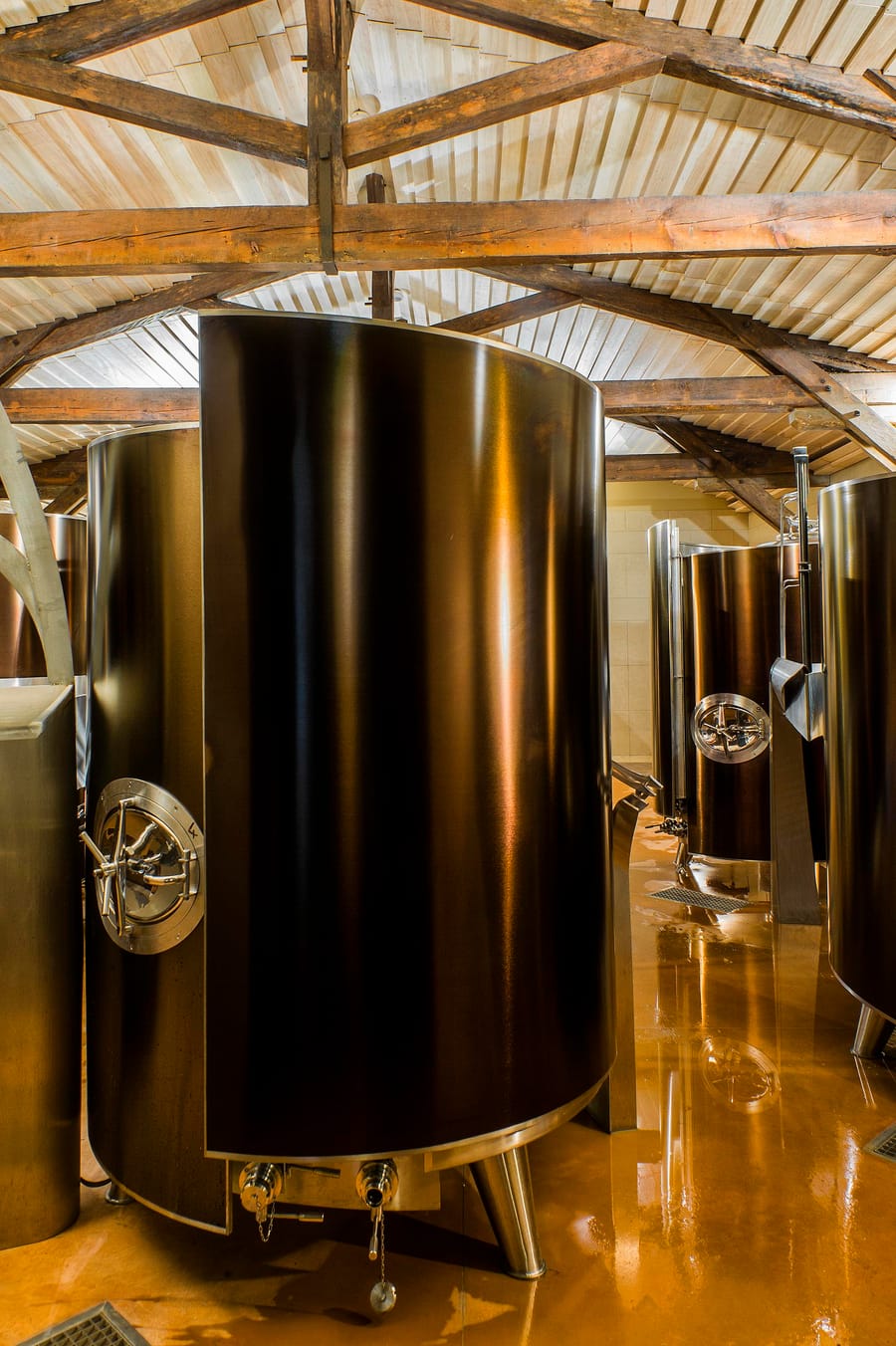 Cuves de vinification en inox sous une charpente en bois dans le cuvier d'un domaine viticole, Château d'Yquem à Sauternes