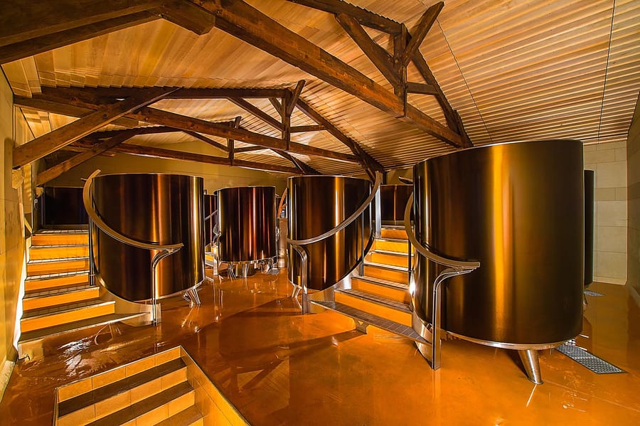 Cuves de vinification métalliques disposées sous une charpente en bois dans un cuvier moderne, Château d'Yquem à Sauternes