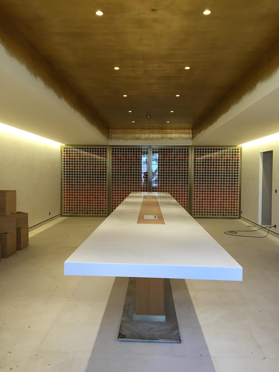 Grande table blanche de dégustation disposée dans une salle moderne au plafond doré avec casiers à vin intégrés, Château d'Yquem à Sauternes
